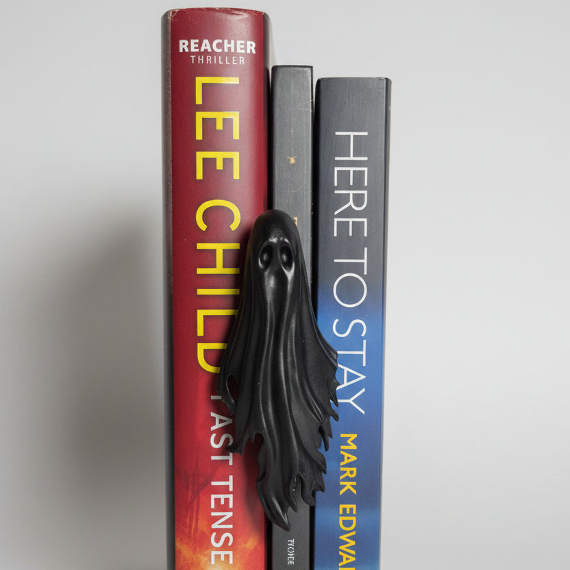 Black gothic ghost spine hugger resting against books on a bookshelf