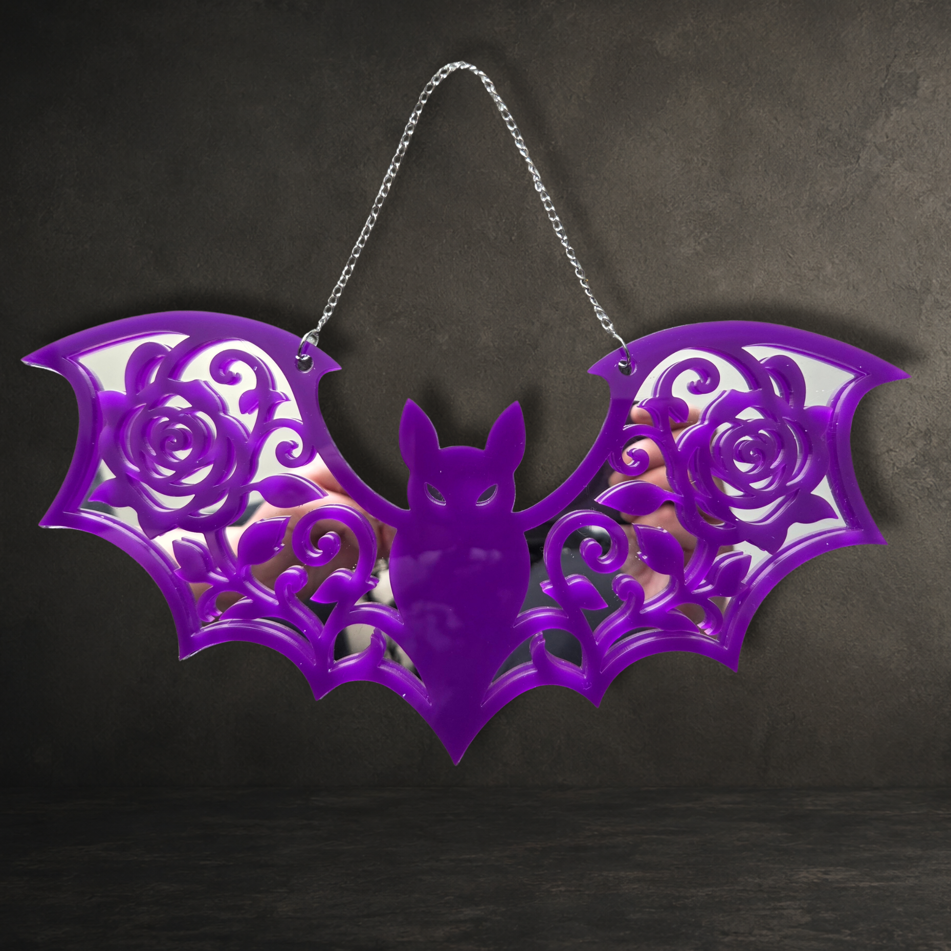 Purple acrylic gothic bat wall mirror with intricate rose detailing and decorative hanging chain.